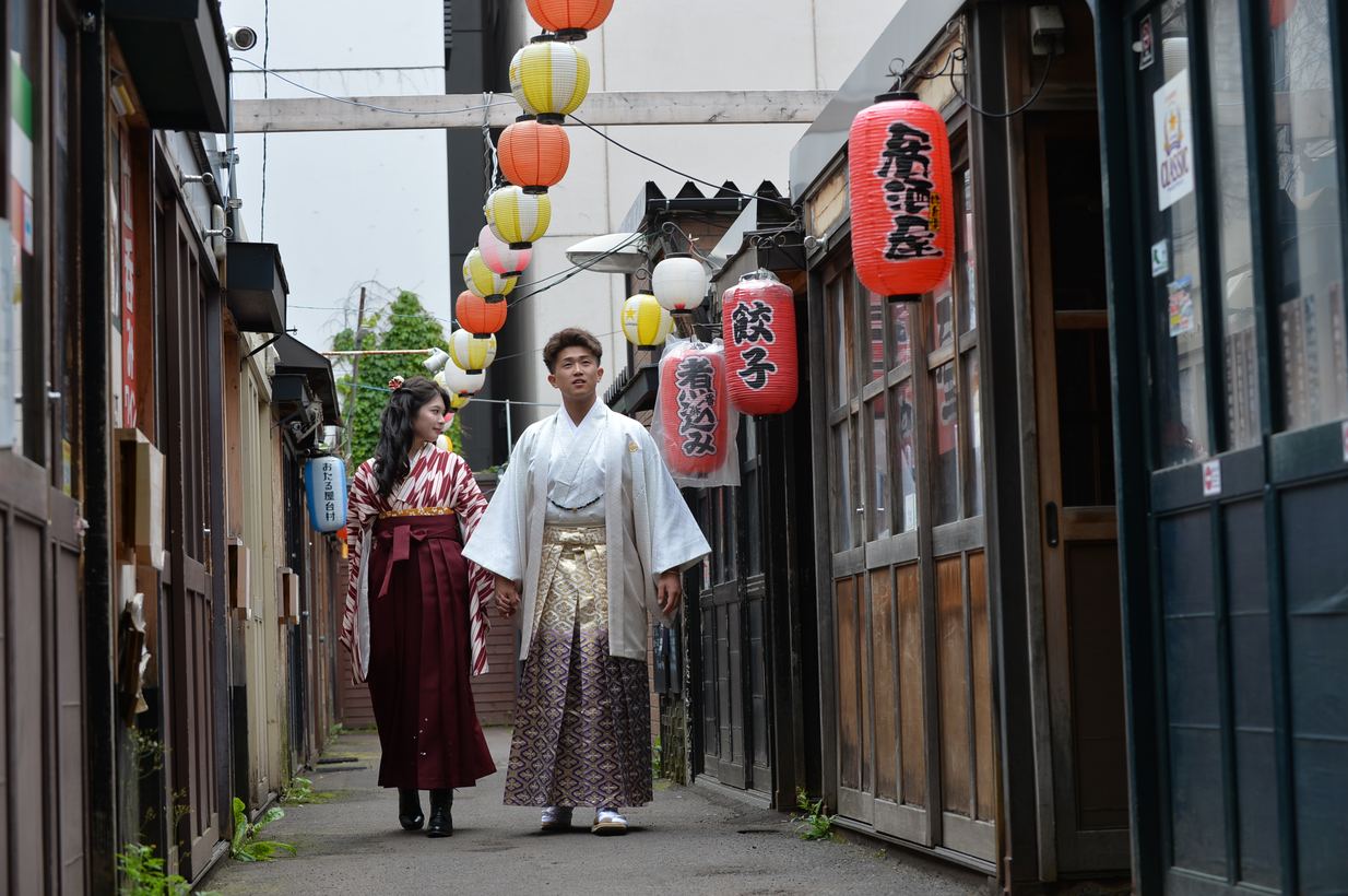 提灯の下がる路地を歩くふたり